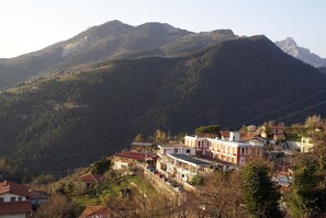 A hillside village with traditional houses and a prominent building with a red roof. - Albergo San Carlo (Massa)