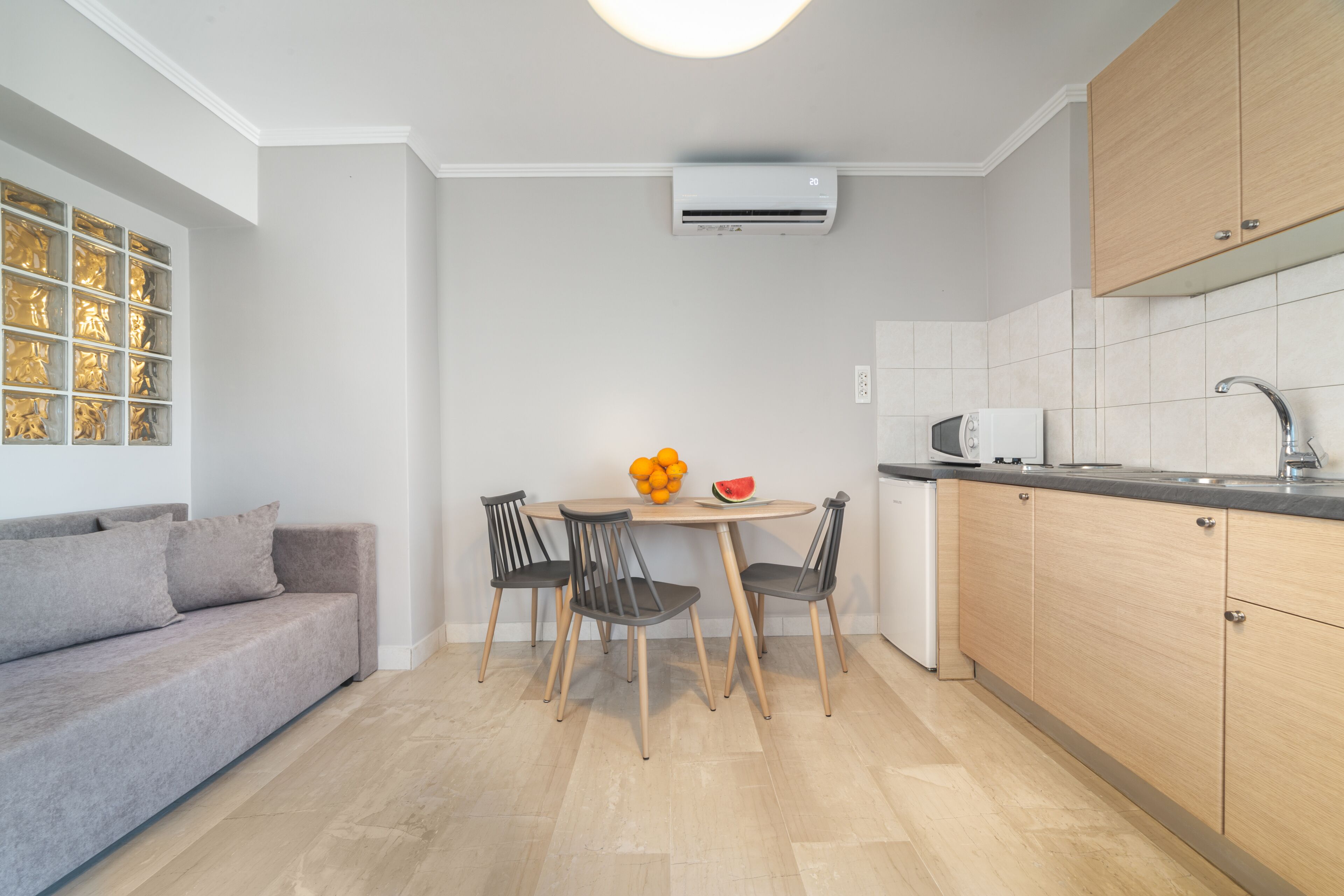 A modern kitchen with a dining table, chairs, a sofa, and a microwave.