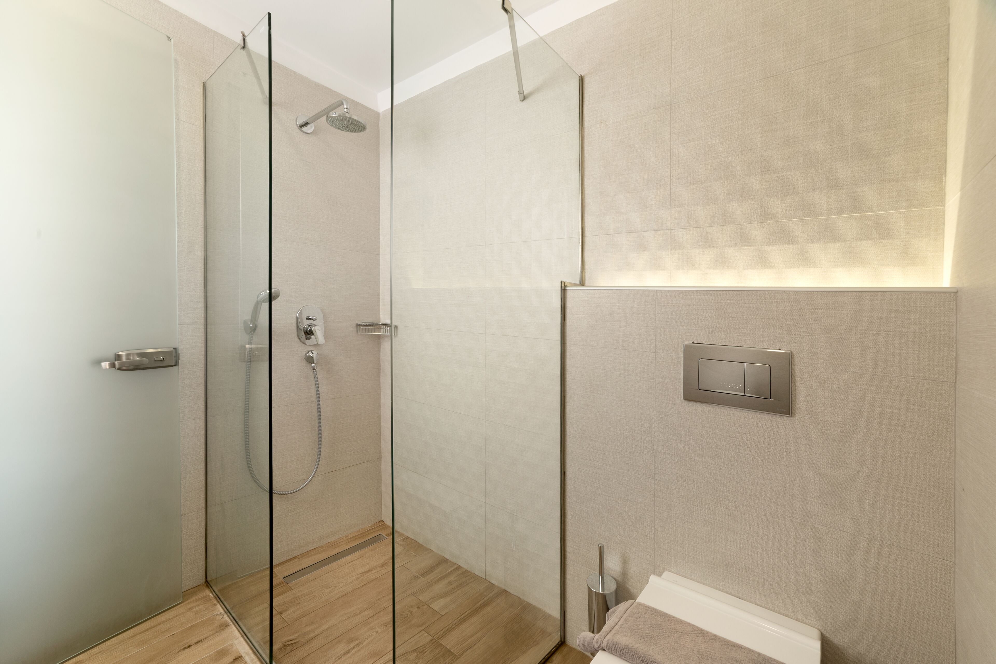 Ein modernes Badezimmer mit Duschkabine aus Glas, Handtuchhalter und einem Lichtschalter an der Wand.