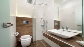 A modern bathroom with a glass shower enclosure, a white toilet, and a large sink with a mirror above it.