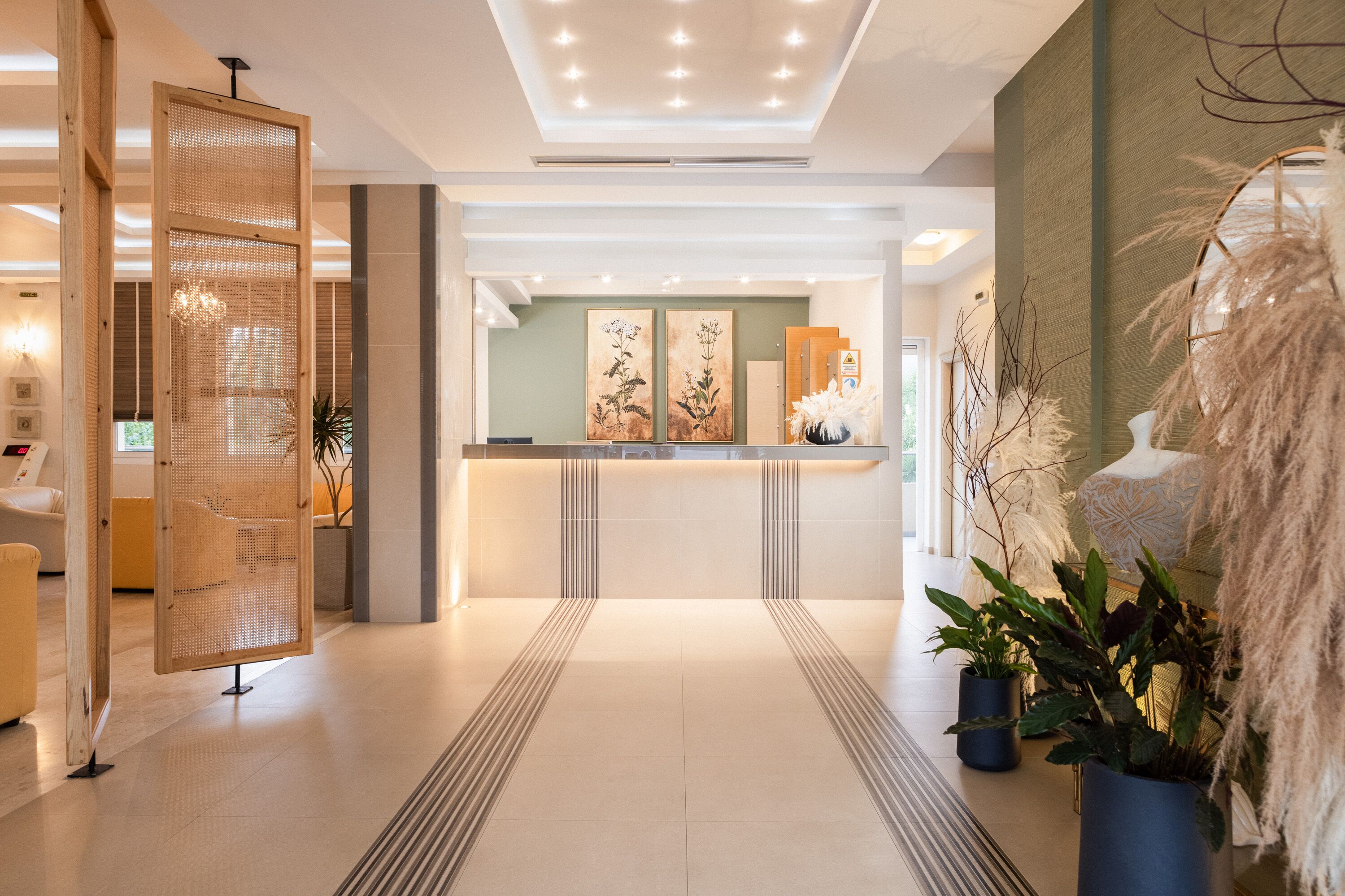 A modern reception area with a wooden partition, a reception desk, and two large floral paintings on the wall.