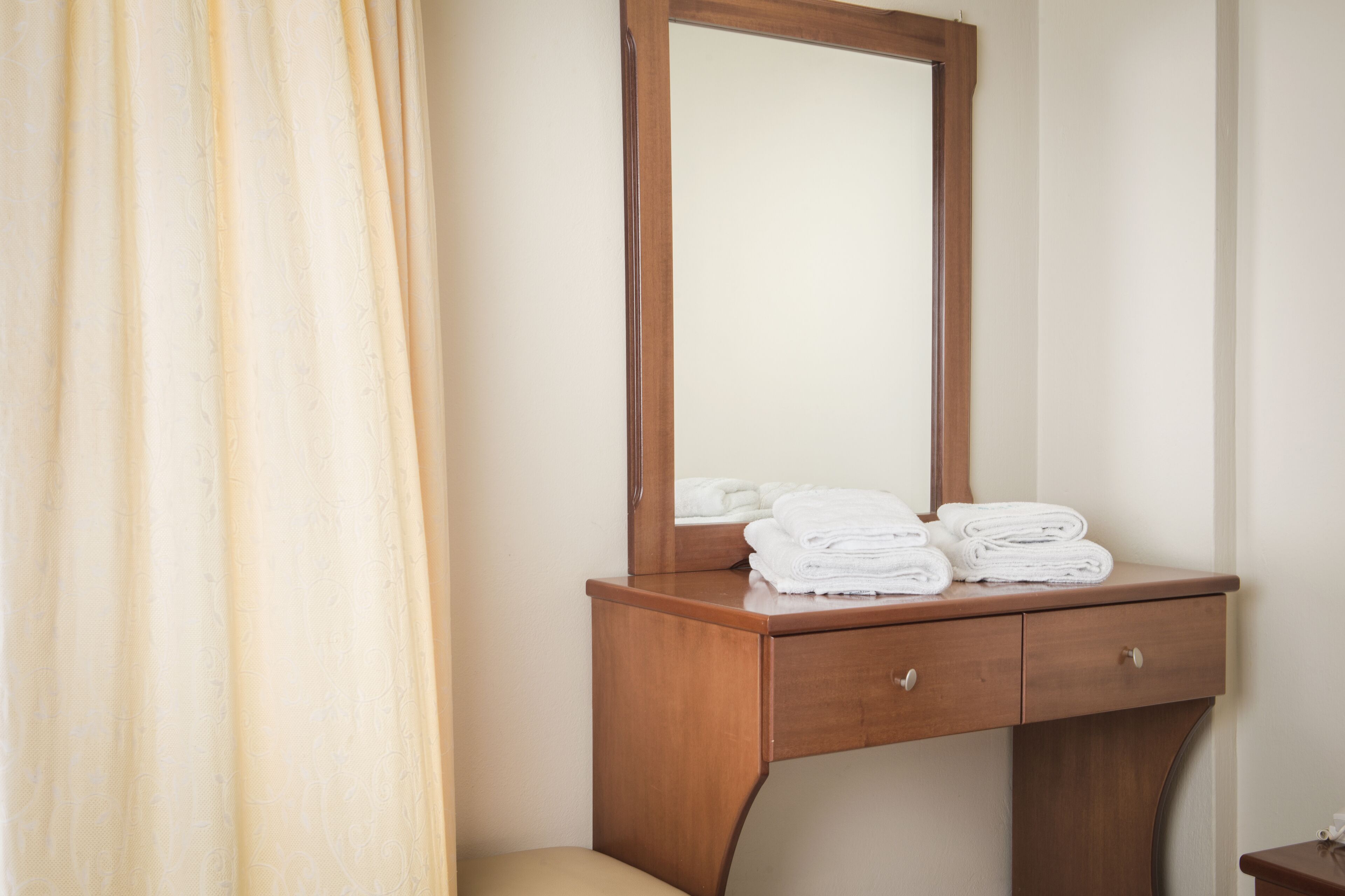 A wooden vanity with a mirror, two drawers, and a towel stack.