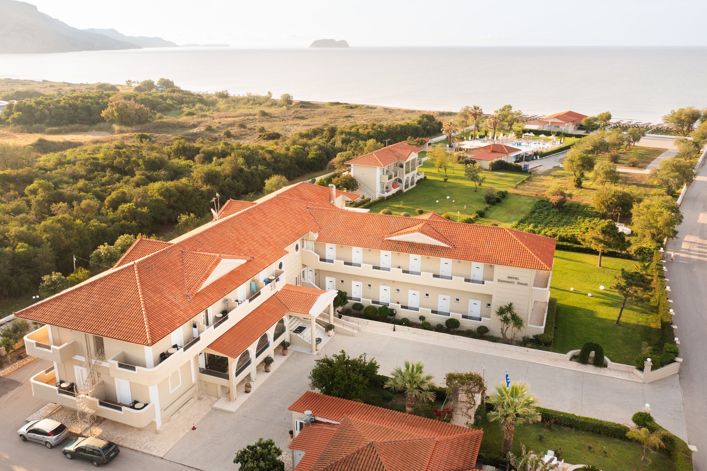 Un hotel con varias construcciones, piscina y vista al mar.