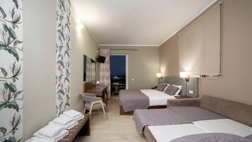 Une chambre d’hôtel avec deux lits, un bureau, une chaise et une vue sur la ville la nuit.