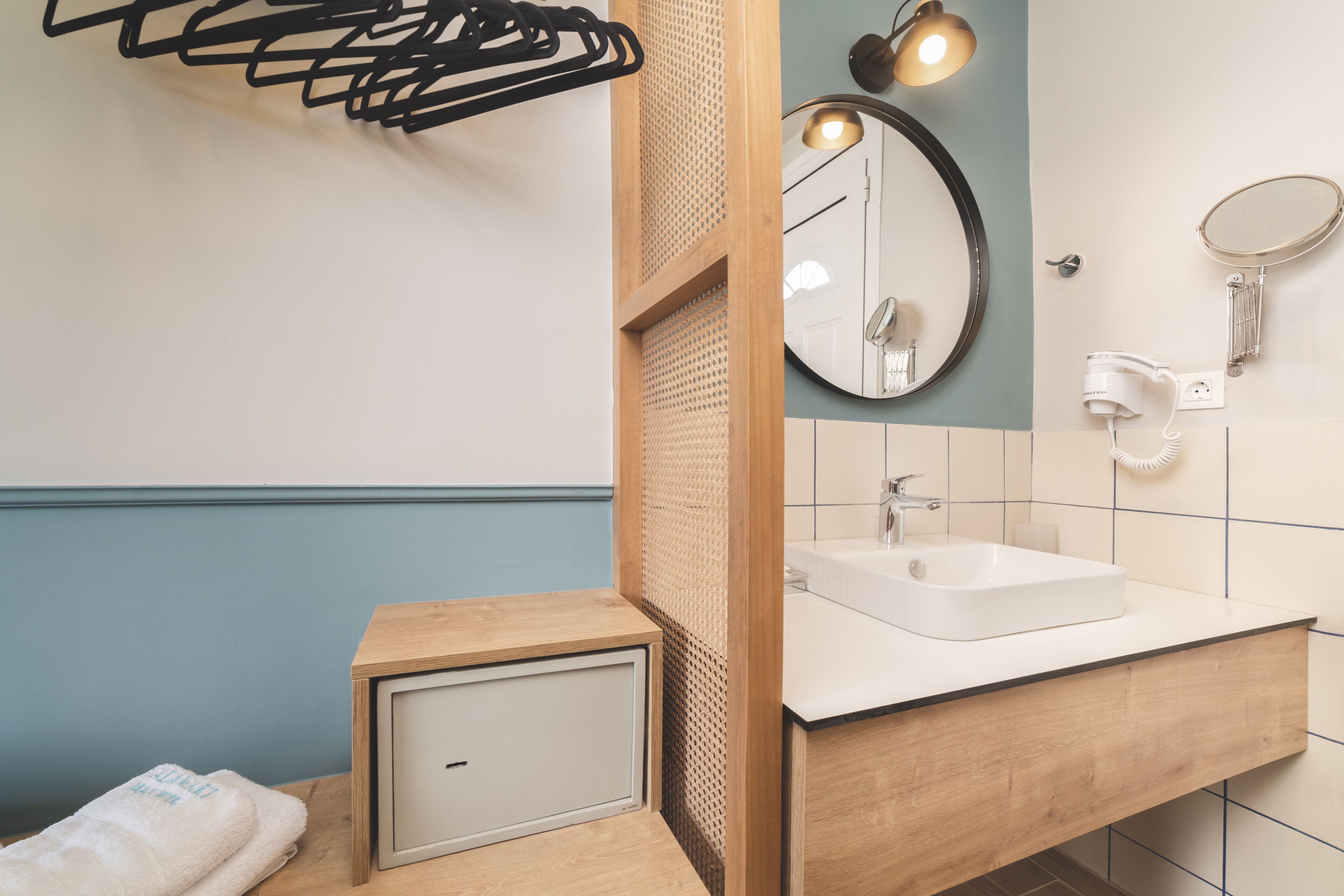 A bathroom with a wooden vanity, a white sink, a mirror, and a towel rack.