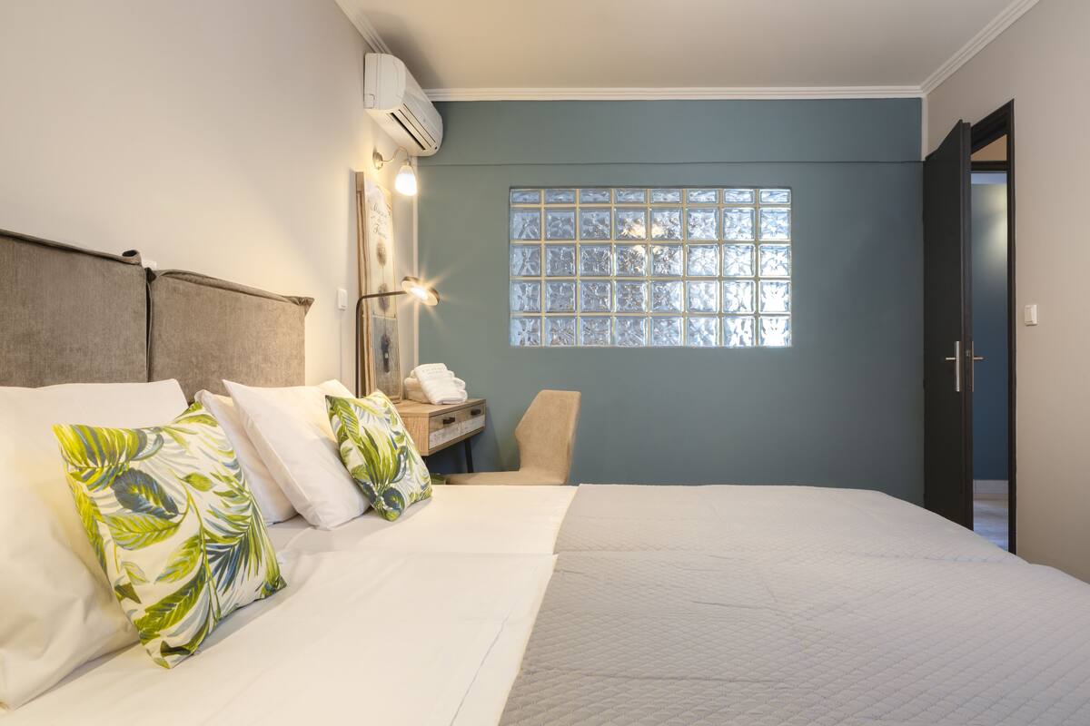 Une chambre d’hôtel comprenant un lit, une table de chevet, une chaise, une fenêtre avec vue et un appareil de climatisation.
