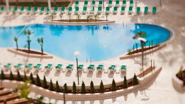 A pool area with lounge chairs and a small boat. - Millennium Palestine Ramallah (Ramallah)