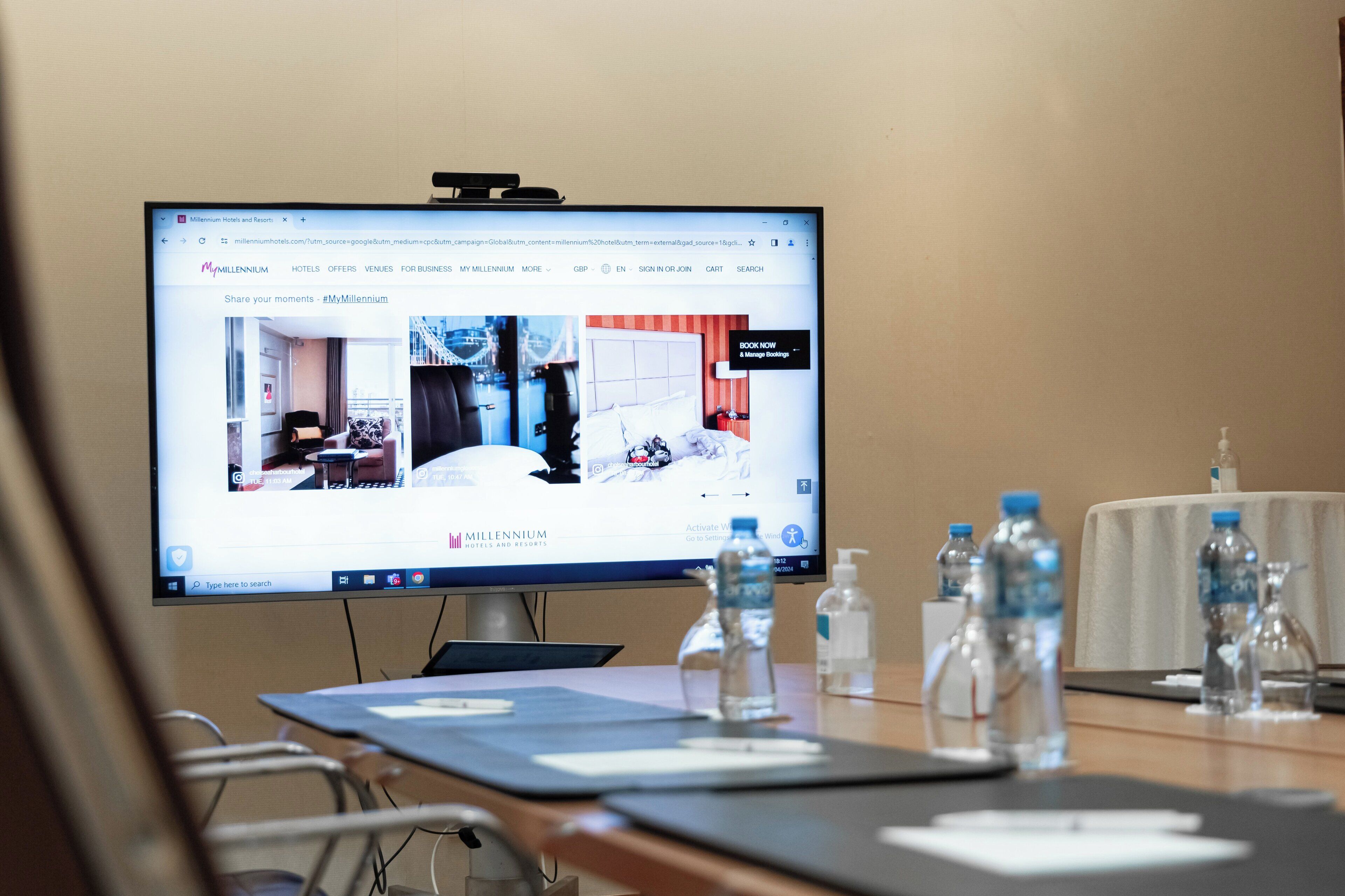 Une chambre d’hôtel avec un lit, un bureau et une chaise. Il y a des bouteilles d’eau sur la table.