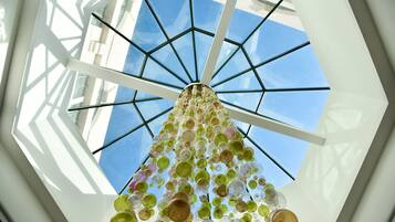 A ceiling with a geometric glass structure and hanging spherical objects.