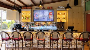 A bar area with a sports screen, bar counter, and seating. - Millennium Palestine Ramallah (Ramallah)