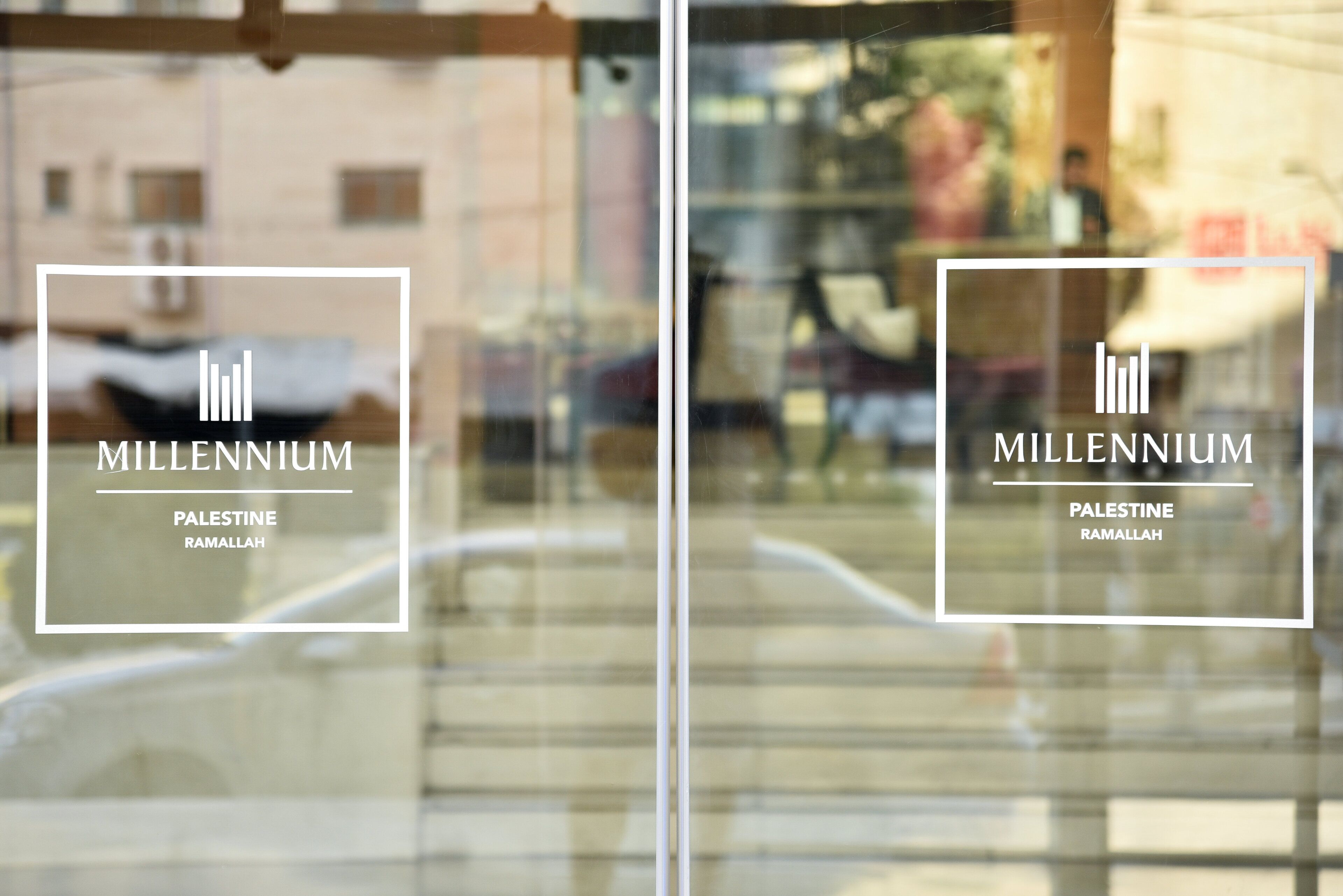 A modern building with a glass facade, labeled 'MILLENNIUM Palestine Ramallah.'