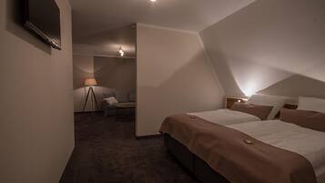 Una habitación de hotel con dos camas, televisión, escritorio y lámpara.