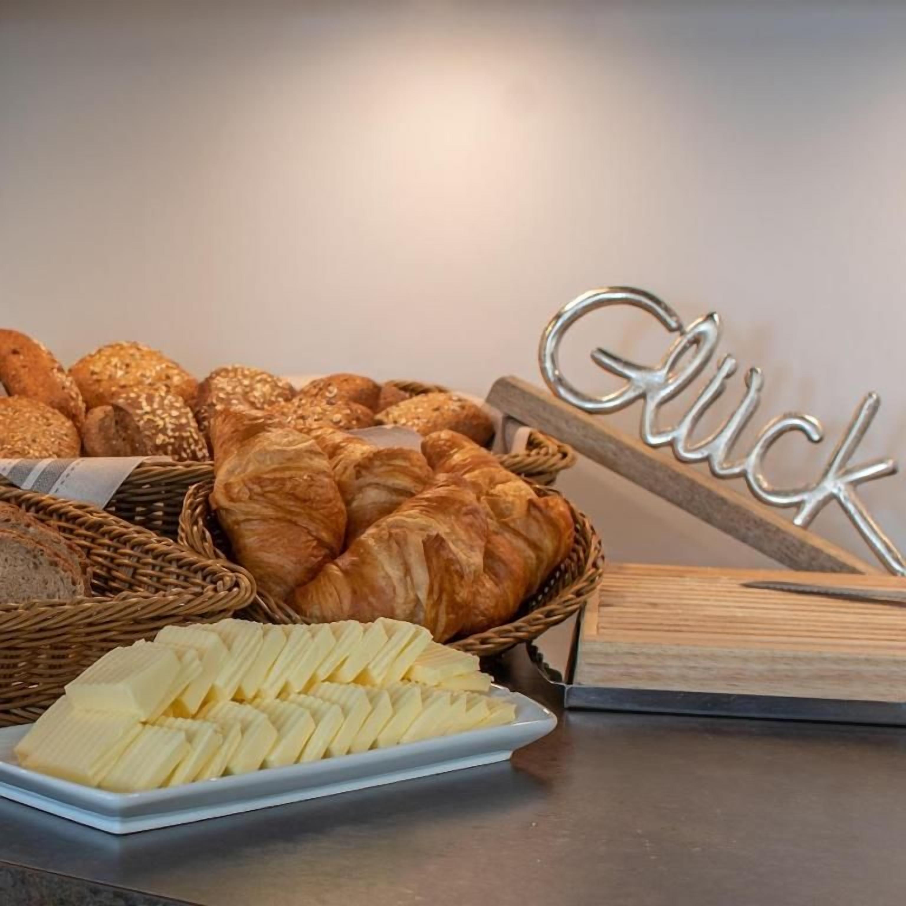 A variety of breads and pastries on a table, including croissants and a sign that reads 'Glück'.