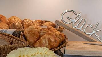 A variety of breads and pastries on a table, including croissants and a sign that reads 'Glück'.
