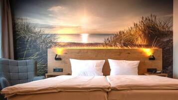A hotel room with a bed, a nightstand, and a headboard with a view of the sea and grass.