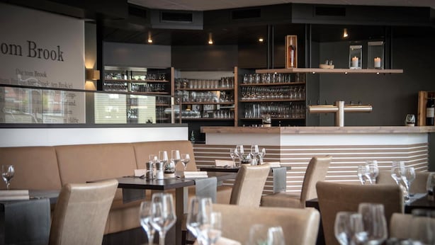A restaurant interior with booths and tables, wine glasses, and shelves of glassware. - Hotel Stadt Aurich (Aurich)