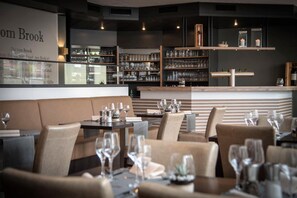 A restaurant interior with booths and tables, wine glasses, and shelves of glassware. - Hotel Stadt Aurich (Aurich)