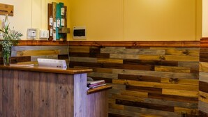 Un espace d’accueil avec un comptoir de réception en bois, un mur jaune et un tableau représentant une mouette.