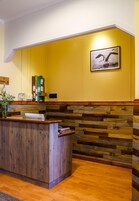 Un área de recepción con un mostrador de madera, una pared amarilla y un cuadro de una gaviota enmarcada.