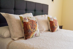 A bed with a tufted headboard and two decorative pillows with a lion design. - Hotel Albatros (Punta Arenas)
