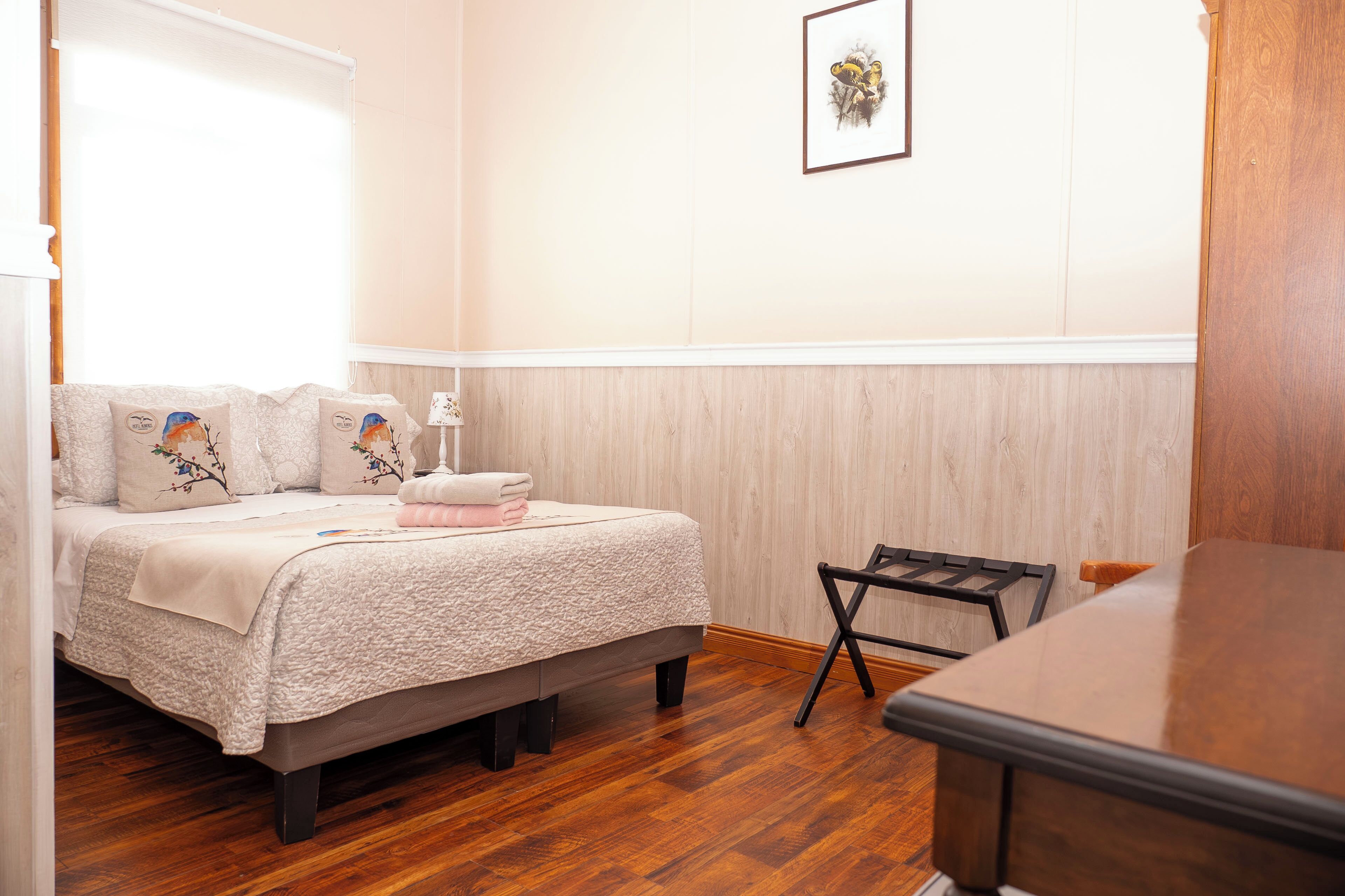 Een slaapkamer met een bed, een stoel, een tafel en een aan de muur hangend schilderij.