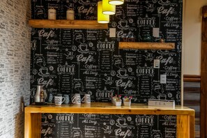 En vägg med kaffetema, där det finns text skrivet med krita, och en trädisk med muggar och en plats för te.