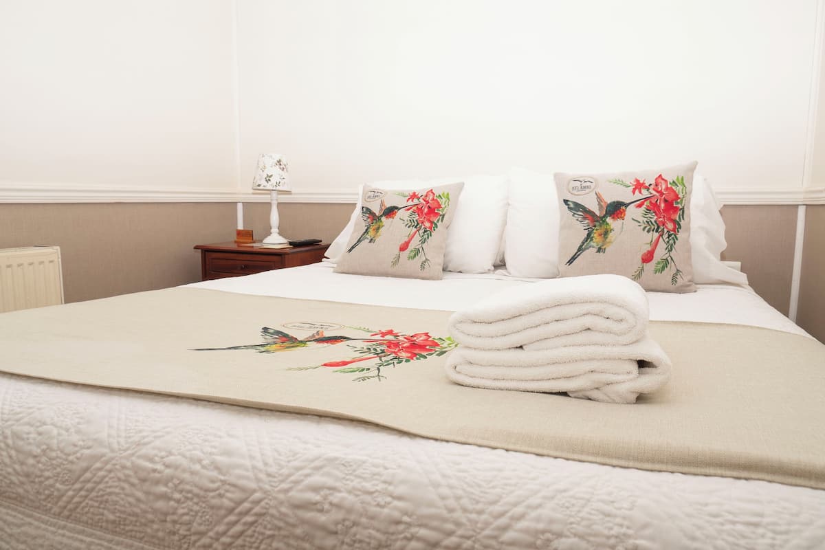 A neatly made bed with a floral pillow and a folded towel.
