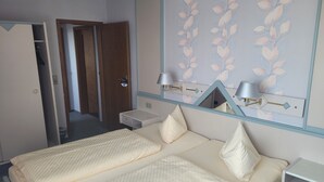 Ein Hotelzimmer mit einem Bett, Nachttischen, einem Spiegel und einer Tür zu einem Flur.
