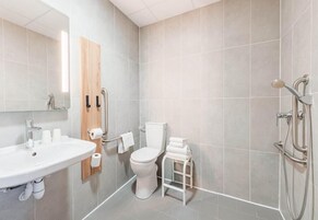 Un baño moderno con lavamanos, inodoro y ducha.