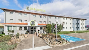 Un hotel B&B con entrada accesible, un estacionamiento con plaza reservada para discapacitados y un letrero que indica prohibido estacionar.