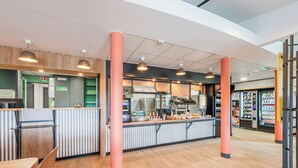 A modern cafe interior with a counter, seating area, and vending machines. - Hotel Roi Soleil Sausheim (Sausheim)