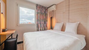 Una habitación de hotel con una cama, un escritorio, una silla y una ventana con cortinas.