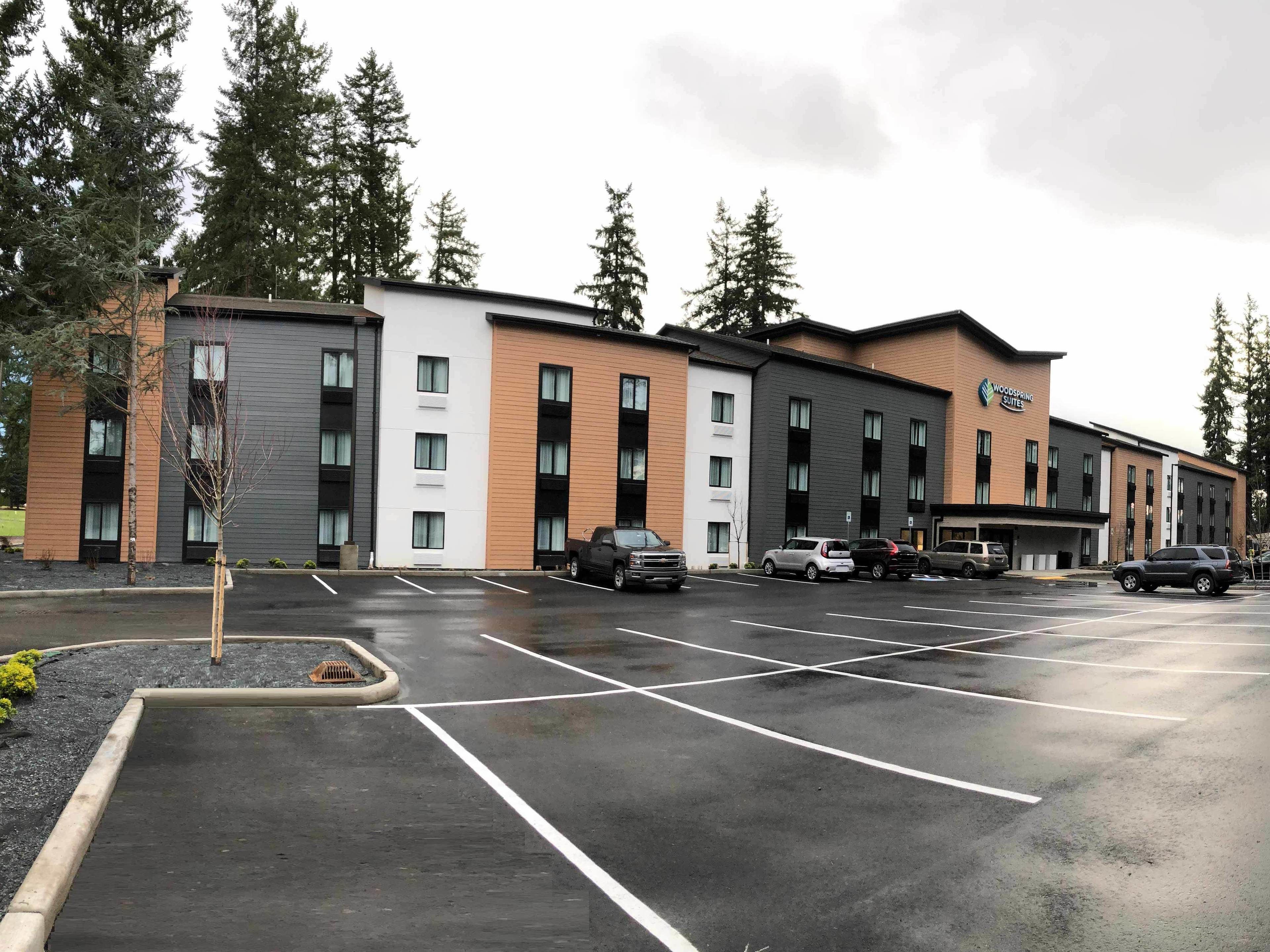 A modern hotel with a parking lot and multiple vehicles.