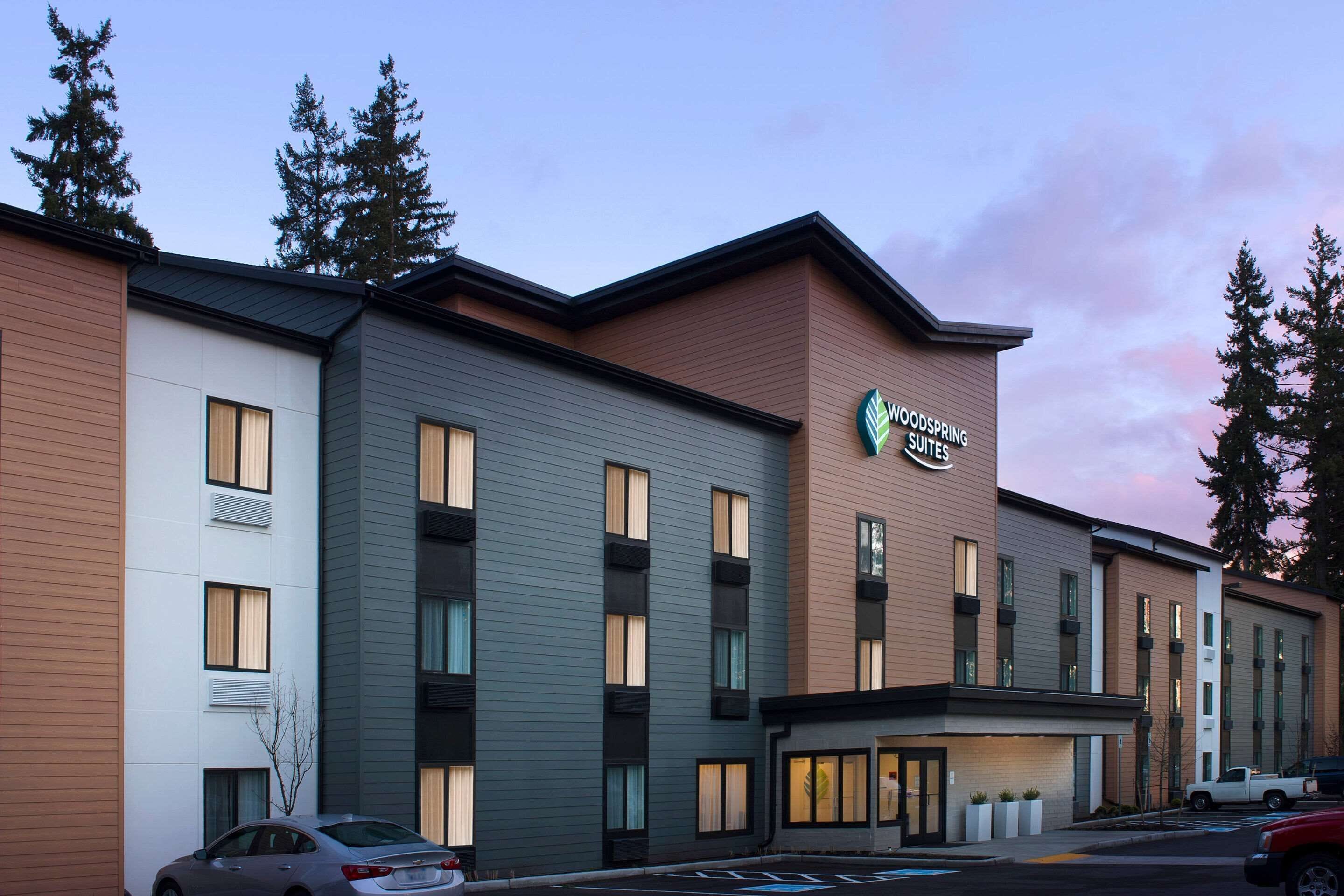 Een hotel met meerdere verdiepingen en een modern ontwerp, met een opvallend bord voor Woodspring Suites.