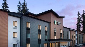 A multi-story hotel with a modern design, featuring a prominent sign for the Woodspring Suites.