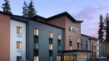 Een hotel met meerdere verdiepingen en een modern ontwerp, met een opvallend bord voor Woodspring Suites.