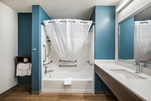 A modern bathroom with a bathtub, shower, and sink.