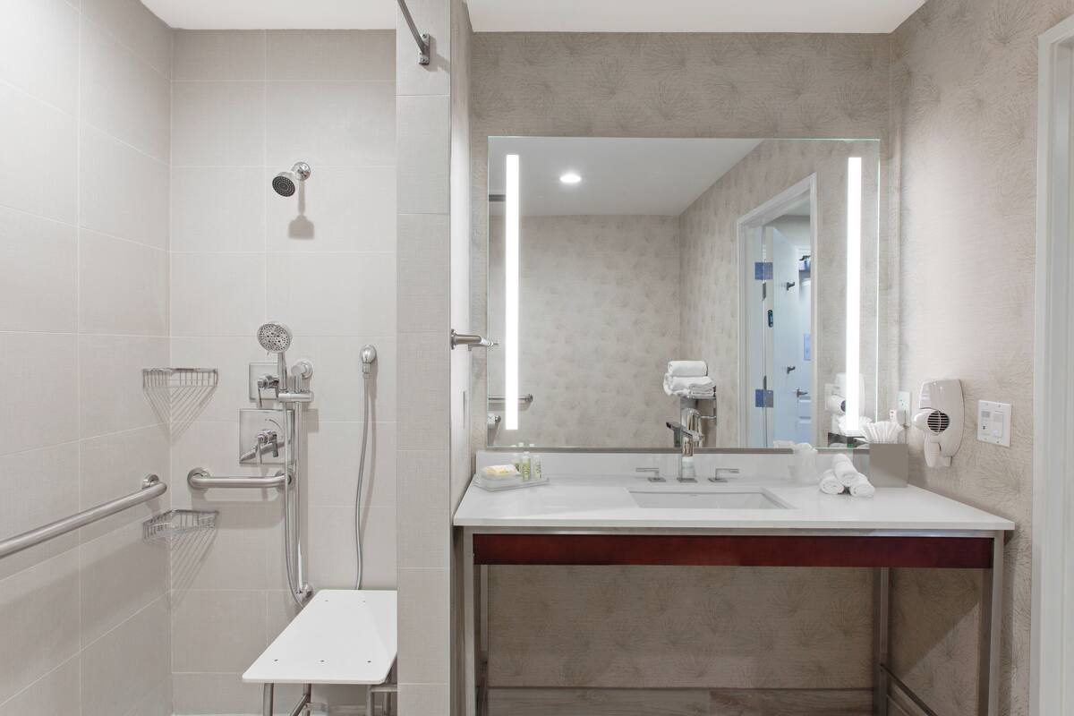 Une salle de bain moderne avec un lavabo blanc, un miroir et une douche.