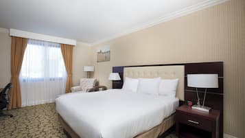 Una habitación de hotel con una cama grande, dos mesitas de noche con lámparas, una silla y un cuadro en la pared.