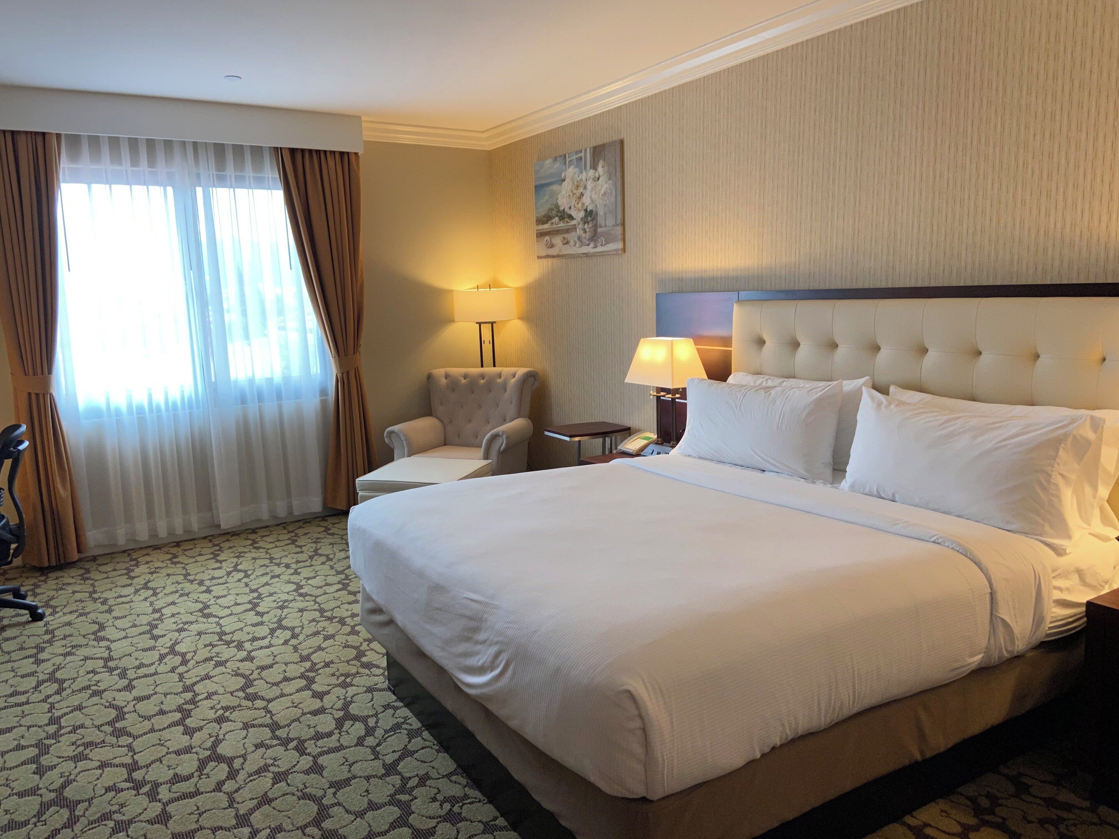 Una habitación de hotel con una cama grande, una silla, un escritorio y una lámpara.