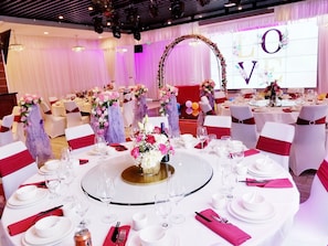 A banquet hall with round tables set for a formal event, featuring floral centerpieces and white tablecloths. - Holiday Inn El Monte - Los Angeles by IHG (El Monte)