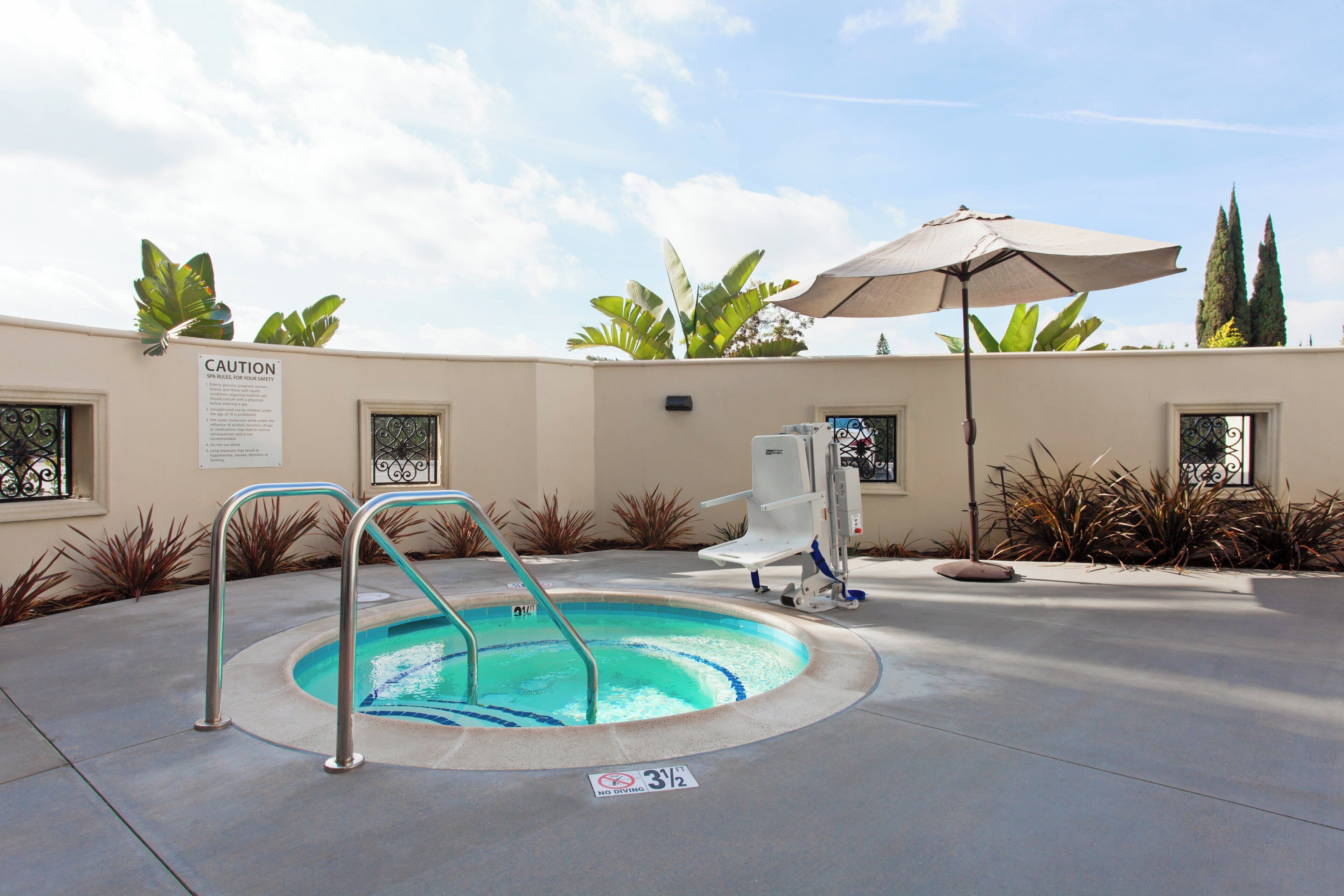 Zona de piscina con un letrero de precaución, un trampolín y una silla para salvavidas.