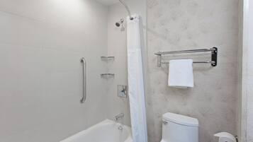 A bathroom with a bathtub, a toilet, and a shower area.