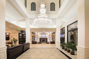 A spacious lobby with a grand chandelier, seating area, and a television screen.