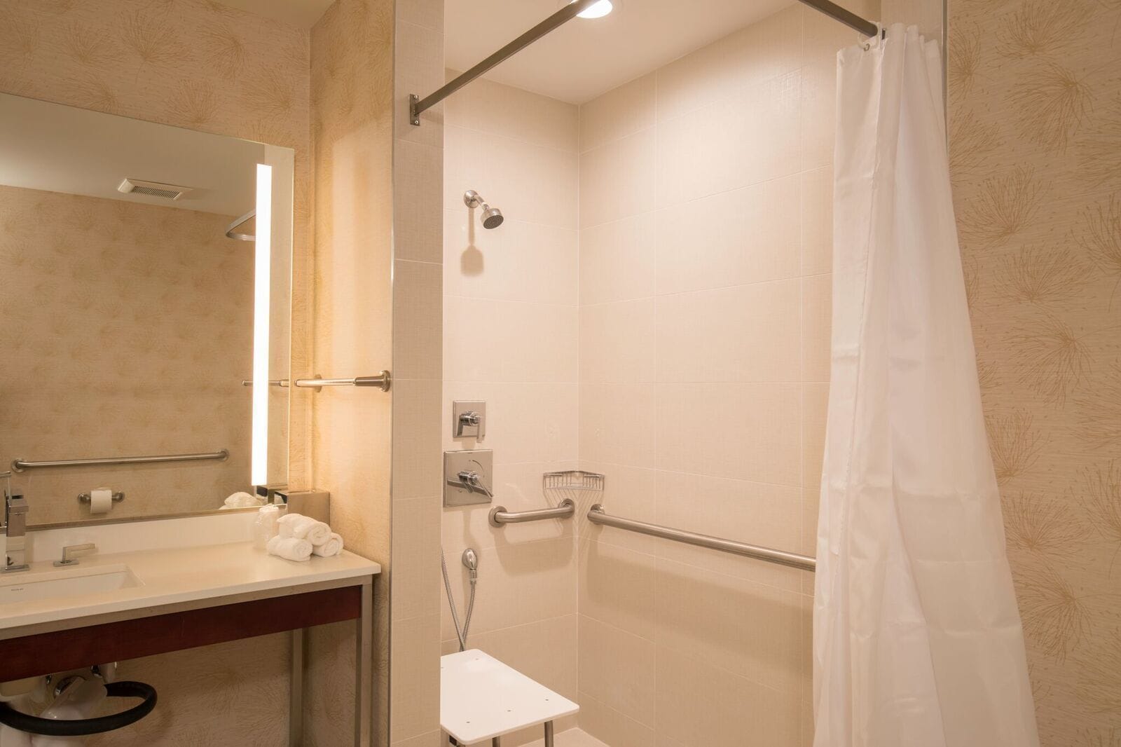 A modern bathroom with a glass shower enclosure, a white sink, and a mirror.