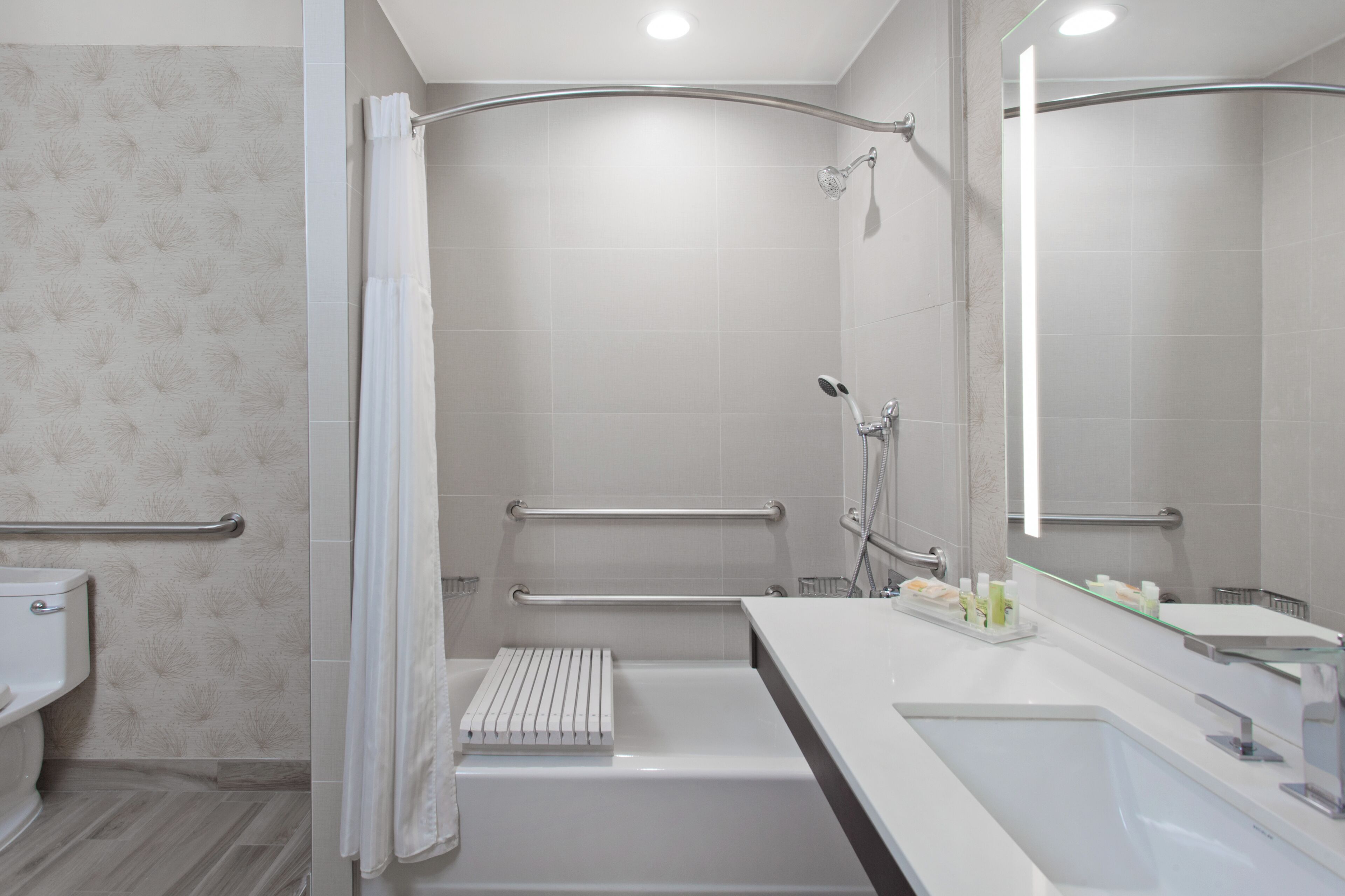 Un baño moderno con ducha, bañera y tocador con espejo.