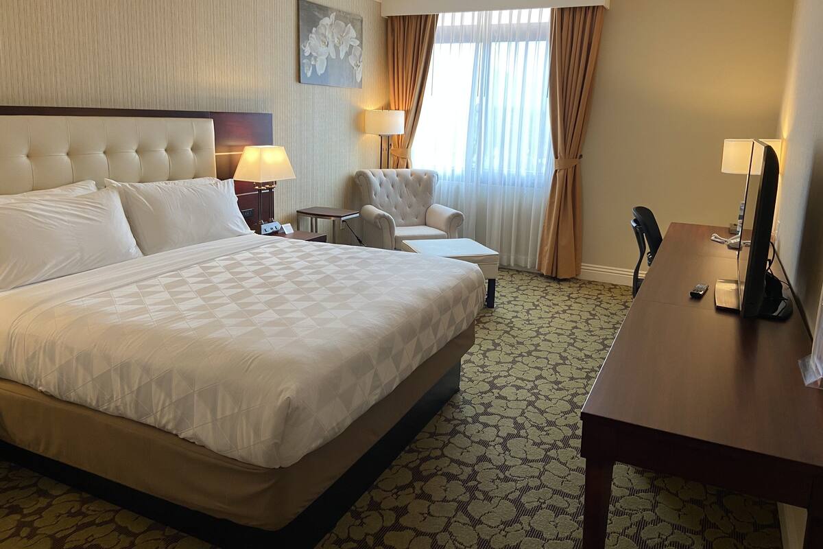 Une chambre d’hôtel avec un grand lit, un bureau, une chaise et un téléviseur.