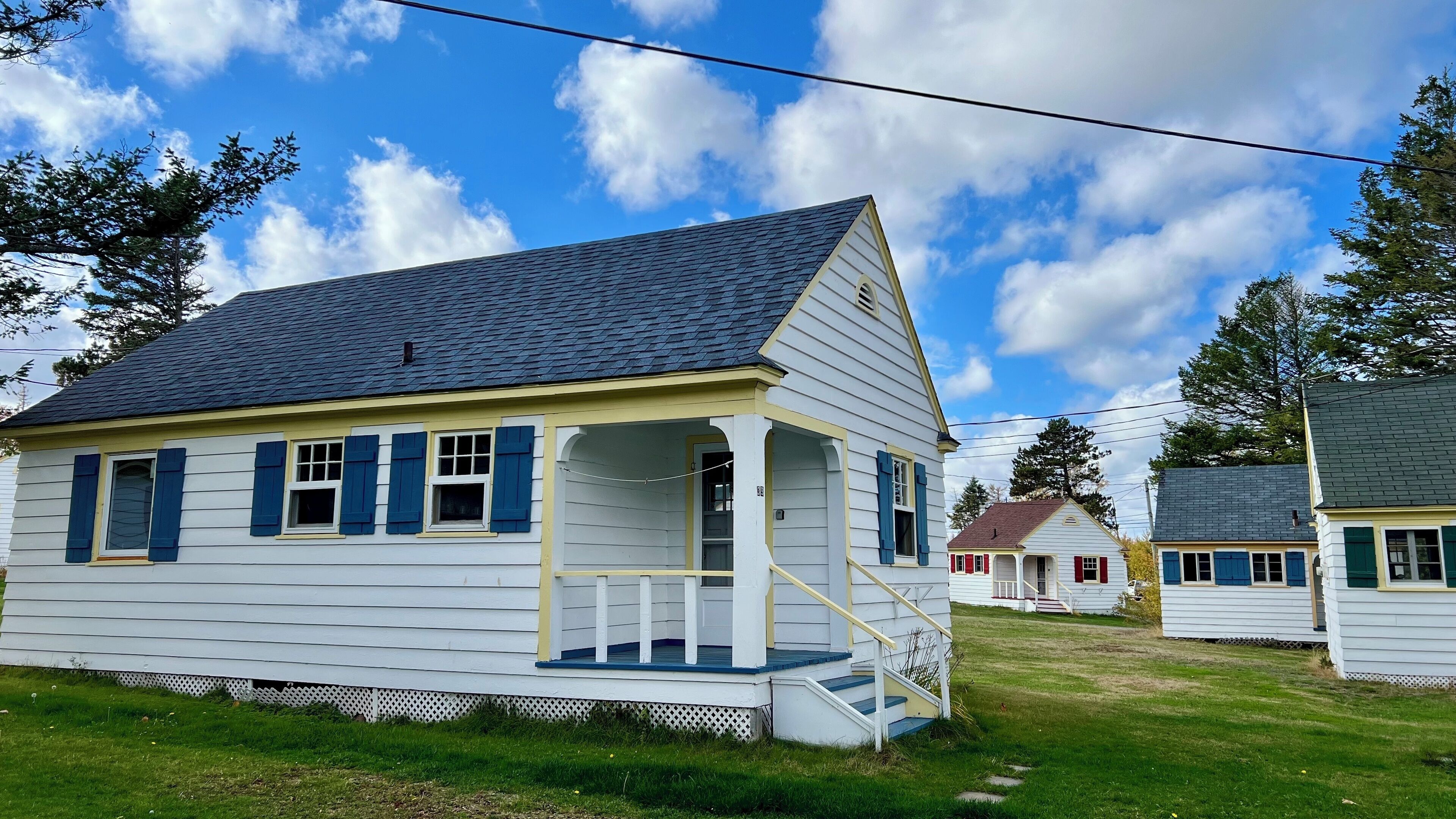A white house with blue shutters and a porch.