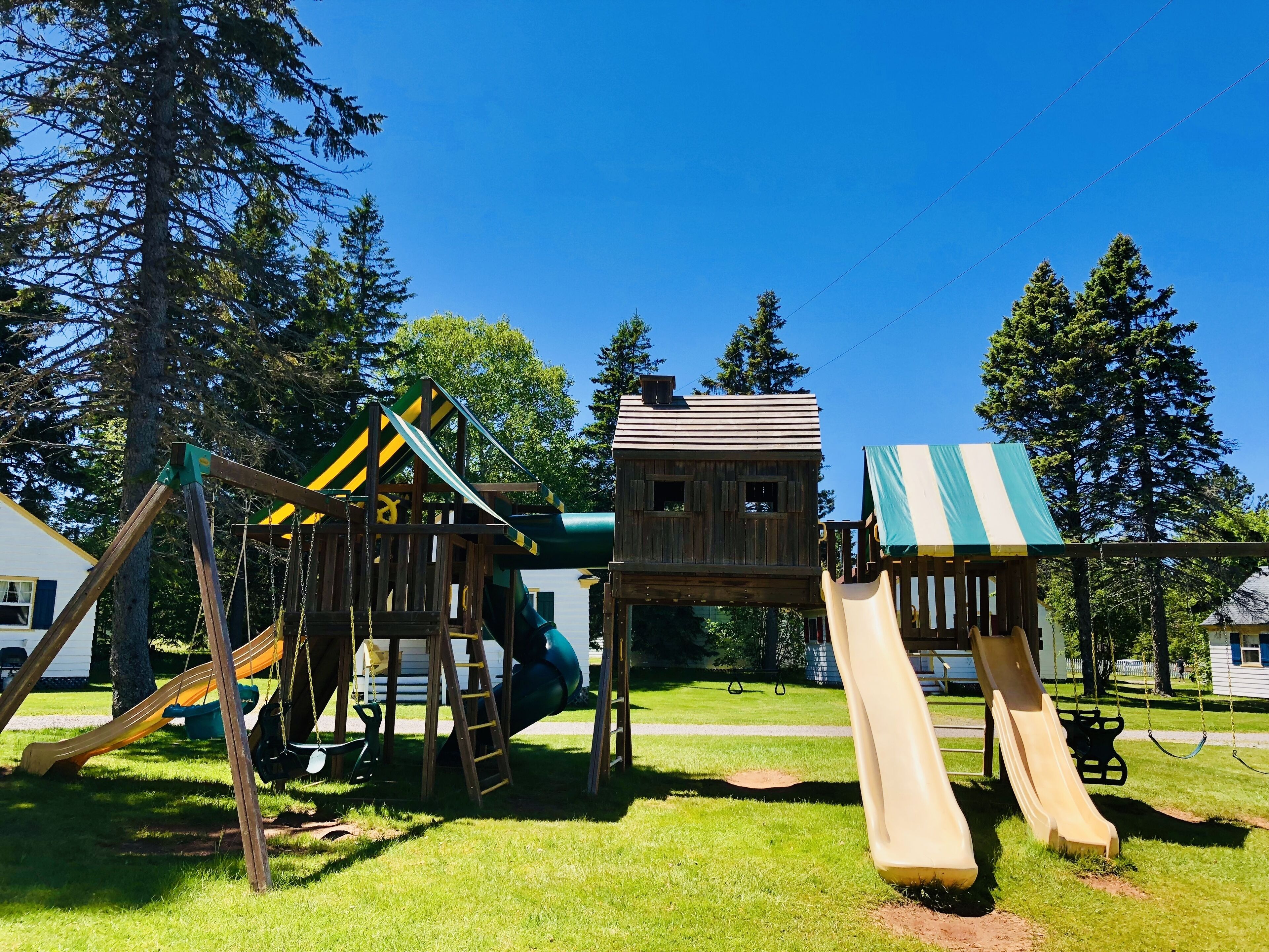 Un parque infantil con tobogán, columpios y una casita de juegos.