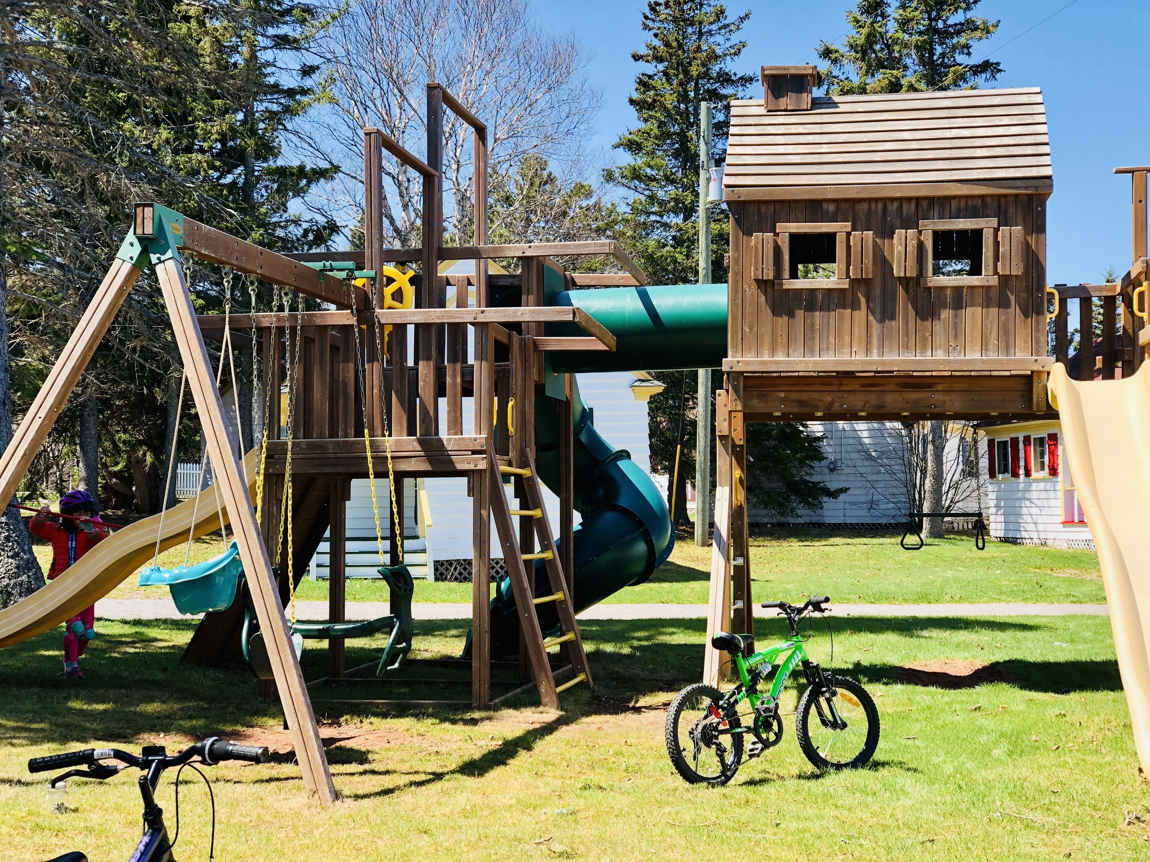 A playground with a wooden climbing structure, a slide, and a bike parked nearby.